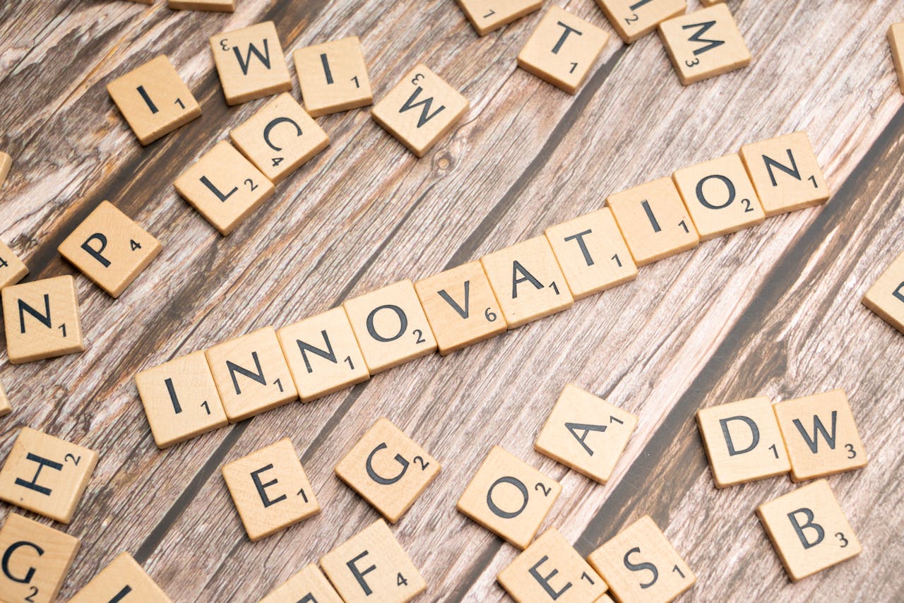 gallery-3 Creative display of 'Innovation' spelled with wooden letter tiles on a wooden surface.