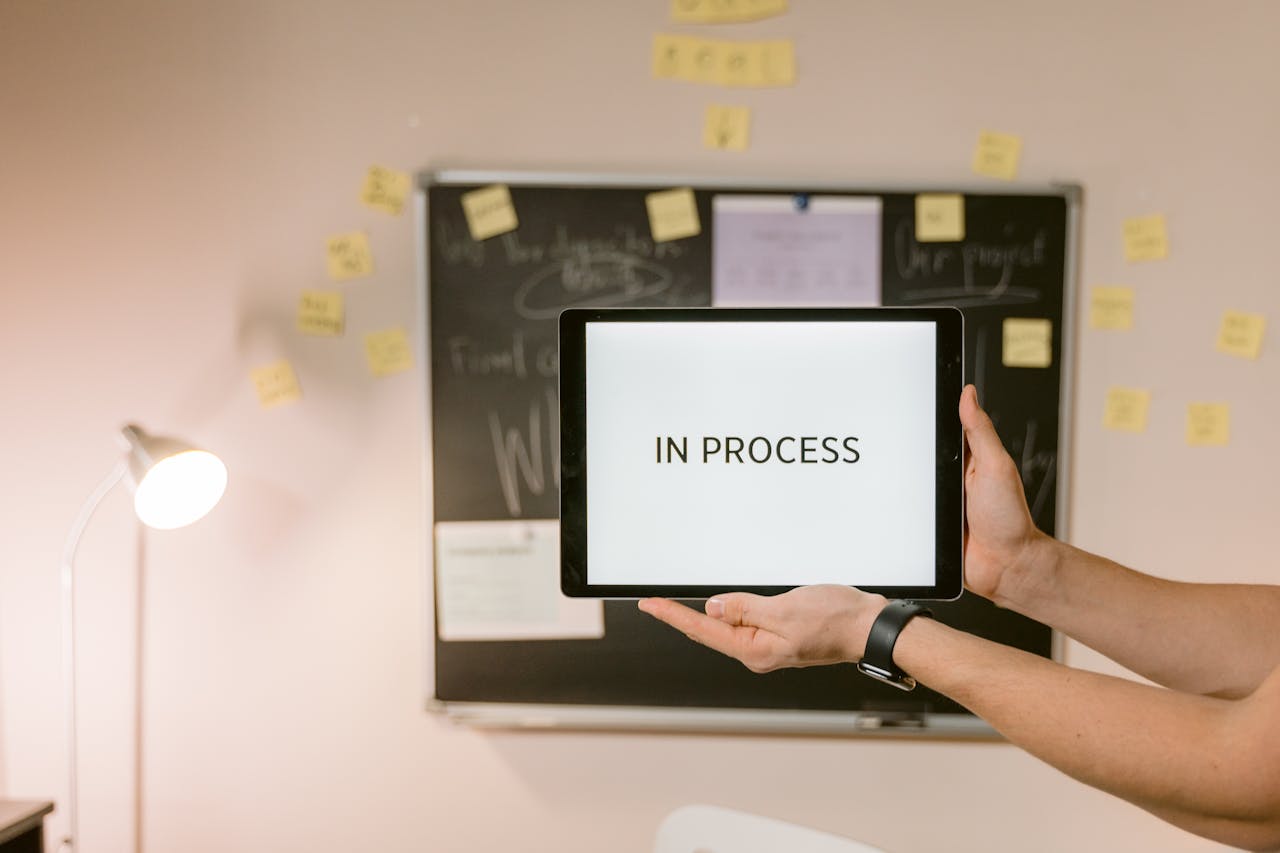 gallery-6 Tablet with 'In Process' text held in an office setting, under analytical review.